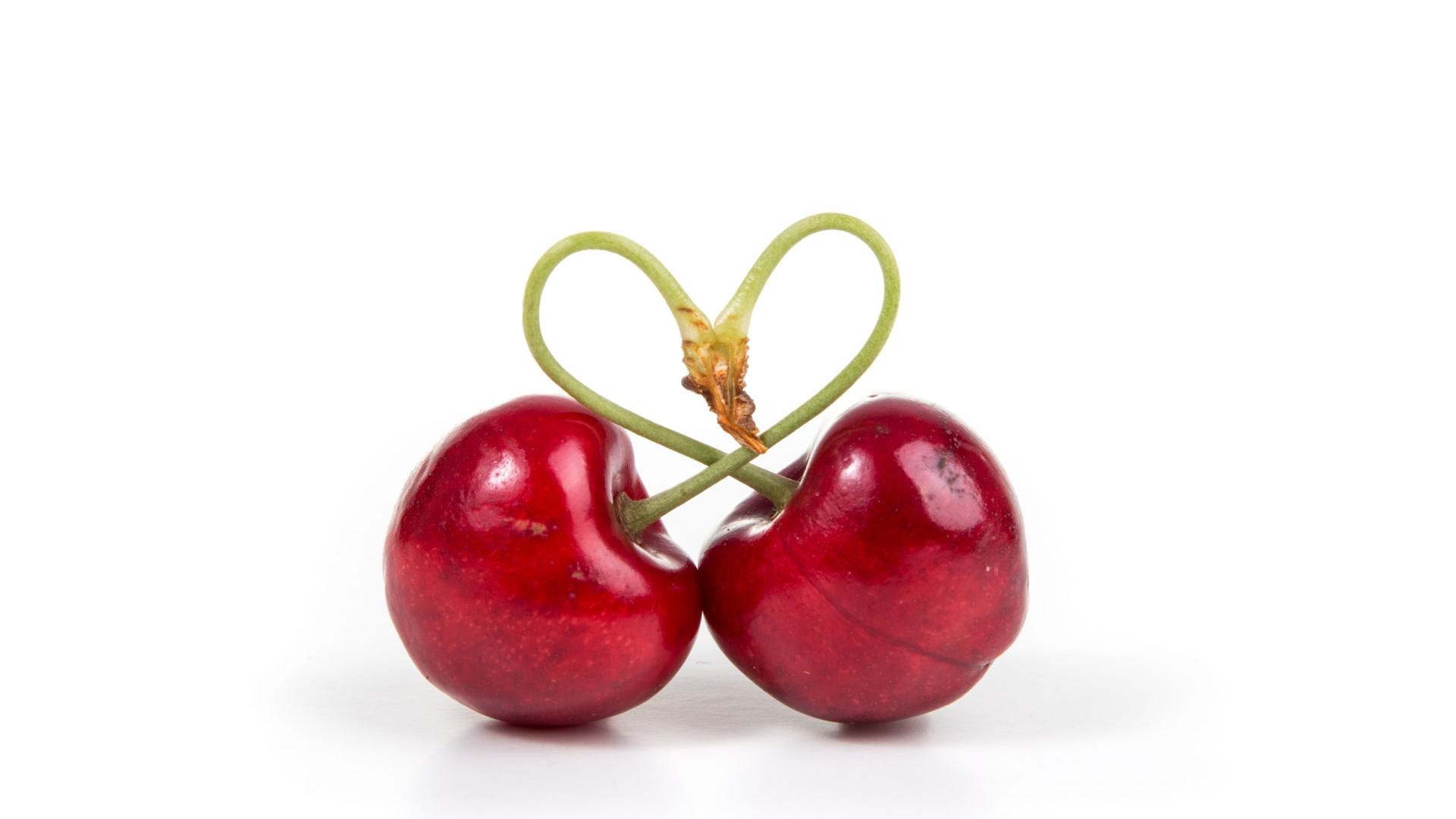 two red cherry fruits on white surface